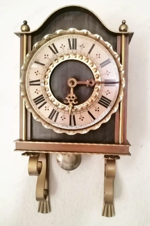 Aranyozott veretekkel díszített elemes fali óra fa házban, működőképes állapotban