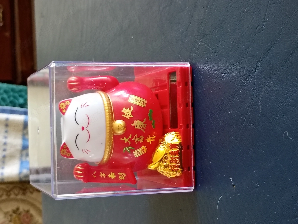 piros színű, átlátszó műanyag dobozba zárt napelem működtetésű maneki-neko (Szerencsehozó Macska) fi