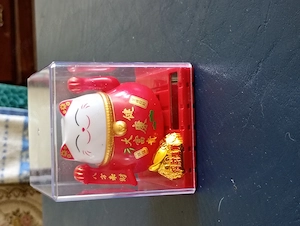 piros színű, átlátszó műanyag dobozba zárt napelem működtetésű maneki-neko (Szerencsehozó Macska) fi